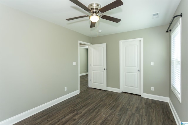 unfurnished bedroom with ceiling fan, dark hardwood / wood-style flooring, and multiple windows