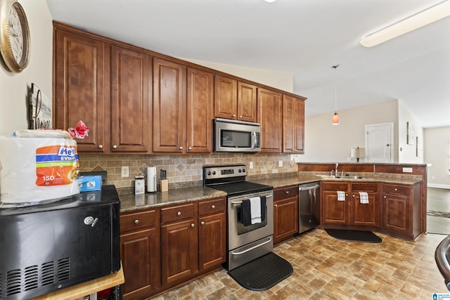 kitchen featuring sink, tasteful backsplash, kitchen peninsula, pendant lighting, and stainless steel appliances