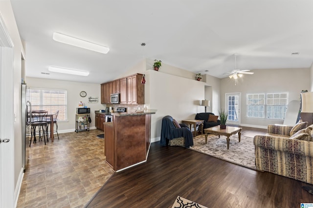 kitchen featuring appliances with stainless steel finishes, hardwood / wood-style floors, tasteful backsplash, lofted ceiling, and kitchen peninsula