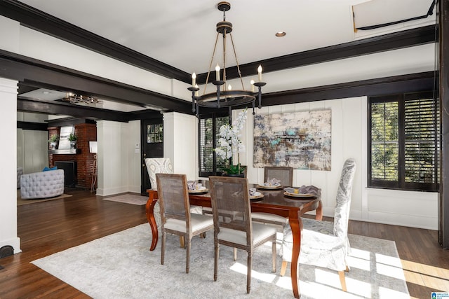 dining space featuring crown molding, a brick fireplace, dark hardwood / wood-style floors, and a chandelier