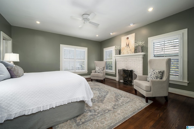 bedroom featuring multiple windows, a brick fireplace, and dark hardwood / wood-style floors