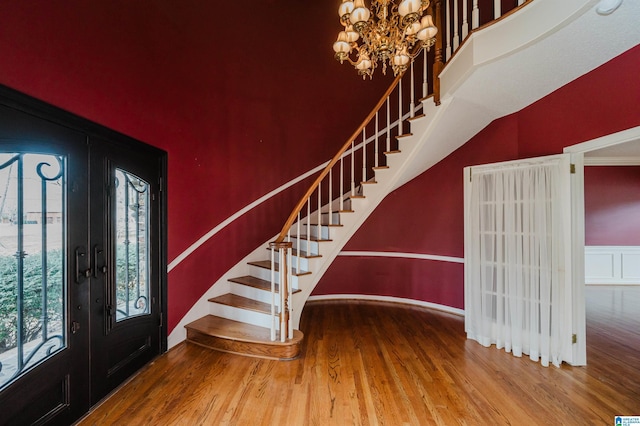 entrance foyer featuring a notable chandelier, a wealth of natural light, french doors, and wood-type flooring