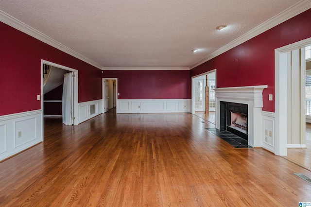 unfurnished living room with a tile fireplace, crown molding, hardwood / wood-style floors, and a textured ceiling