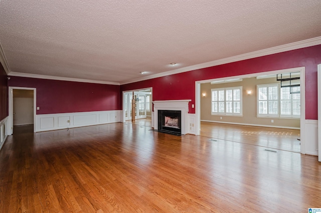 unfurnished living room featuring wood-type flooring, ornamental molding, and a textured ceiling