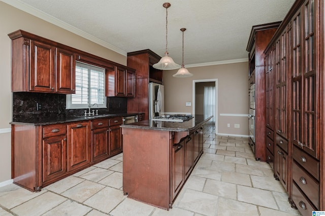 kitchen with appliances with stainless steel finishes, decorative light fixtures, sink, backsplash, and a center island