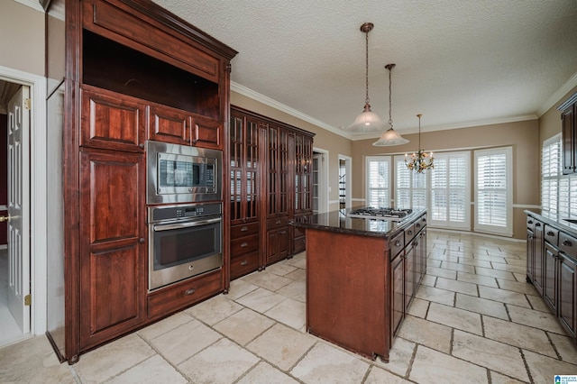 kitchen with appliances with stainless steel finishes, hanging light fixtures, a center island, a textured ceiling, and a chandelier