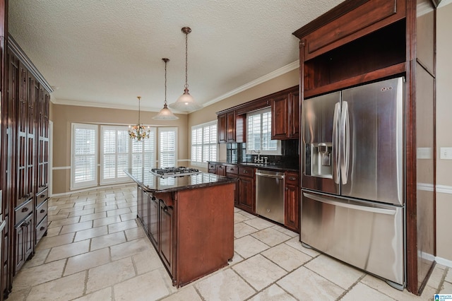 kitchen featuring sink, appliances with stainless steel finishes, hanging light fixtures, a textured ceiling, and a kitchen island