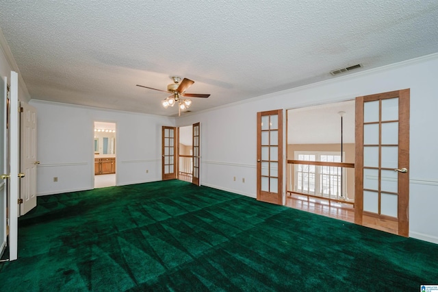 carpeted empty room featuring crown molding, french doors, and a textured ceiling