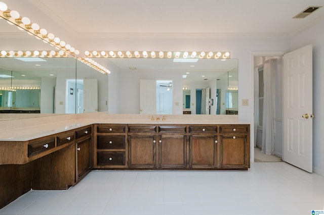 bathroom with ornamental molding, vanity, ceiling fan, and a skylight