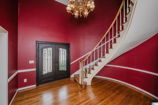 foyer entrance with hardwood / wood-style flooring, french doors, and a notable chandelier