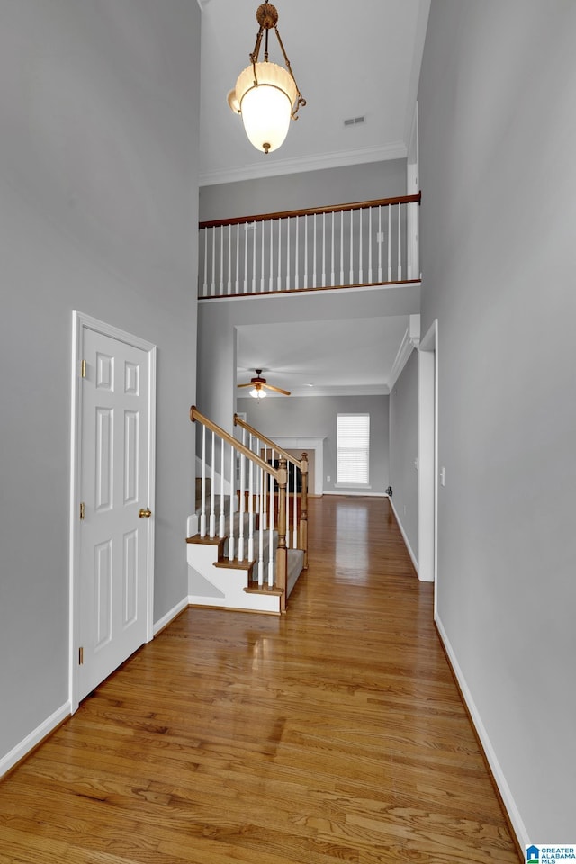 entryway with crown molding, ceiling fan, light hardwood / wood-style flooring, and a high ceiling