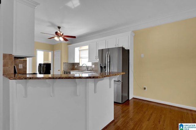 kitchen featuring white cabinetry, stainless steel fridge, a kitchen breakfast bar, and kitchen peninsula