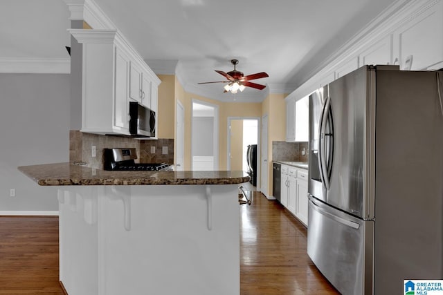 kitchen featuring white cabinetry, stainless steel appliances, kitchen peninsula, and a breakfast bar area