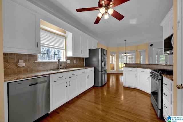 kitchen with dark wood-type flooring, stainless steel appliances, light stone counters, white cabinets, and decorative light fixtures