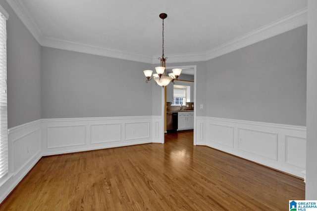 unfurnished dining area with hardwood / wood-style flooring, crown molding, and a chandelier