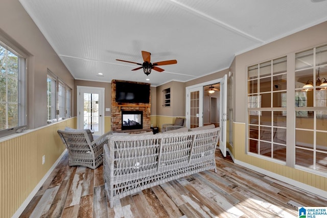 living room featuring a stone fireplace, ceiling fan, and light hardwood / wood-style flooring