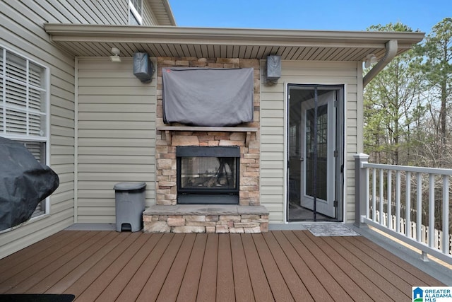 wooden deck with area for grilling and an outdoor stone fireplace