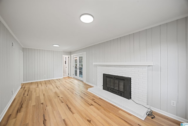 unfurnished living room with crown molding, wood-type flooring, a fireplace, and wood walls