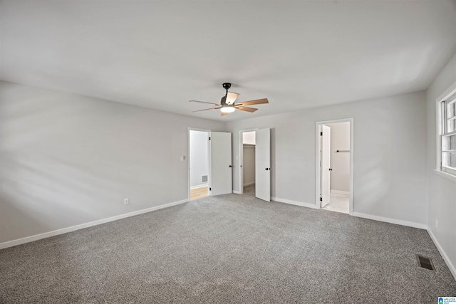 unfurnished bedroom with ceiling fan, ensuite bathroom, carpet, and a walk in closet