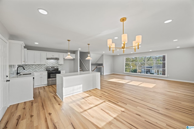 kitchen with sink, white cabinets, decorative backsplash, hanging light fixtures, and stainless steel range with electric stovetop