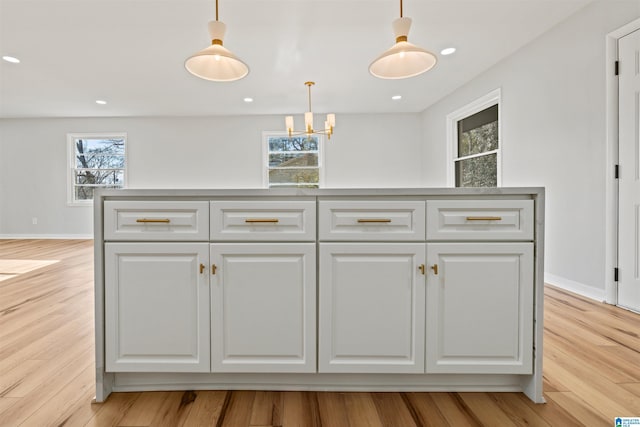 kitchen featuring a center island, pendant lighting, white cabinets, and light wood-type flooring