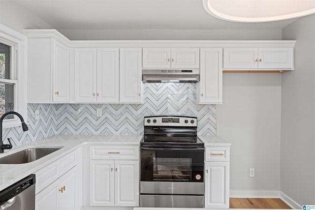 kitchen featuring sink, backsplash, stainless steel appliances, light stone counters, and white cabinets