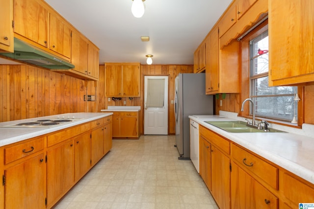 kitchen featuring sink, white appliances, and wooden walls