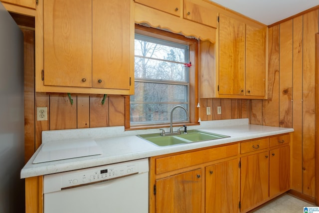 kitchen with dishwasher, sink, stainless steel fridge, and wood walls