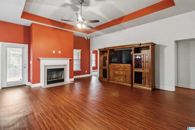 unfurnished living room featuring dark hardwood / wood-style floors, a premium fireplace, and a raised ceiling