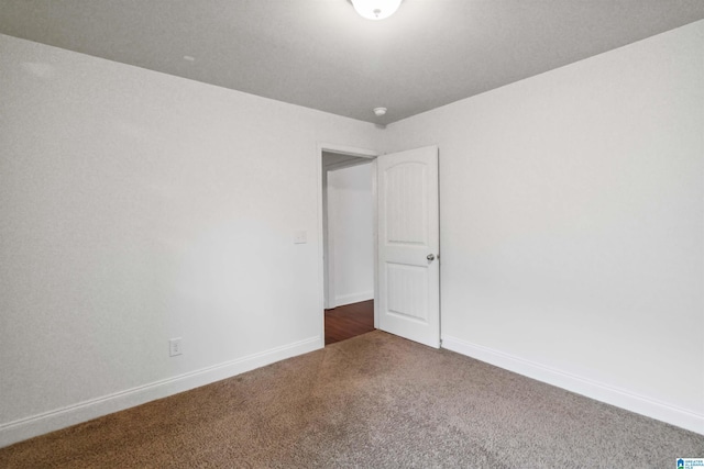 unfurnished room featuring dark carpet