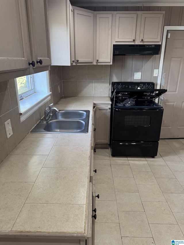 kitchen featuring tasteful backsplash, black electric range oven, light tile patterned floors, and sink