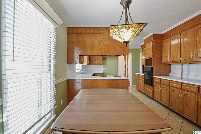 kitchen featuring decorative light fixtures, oven, light tile patterned floors, crown molding, and plenty of natural light