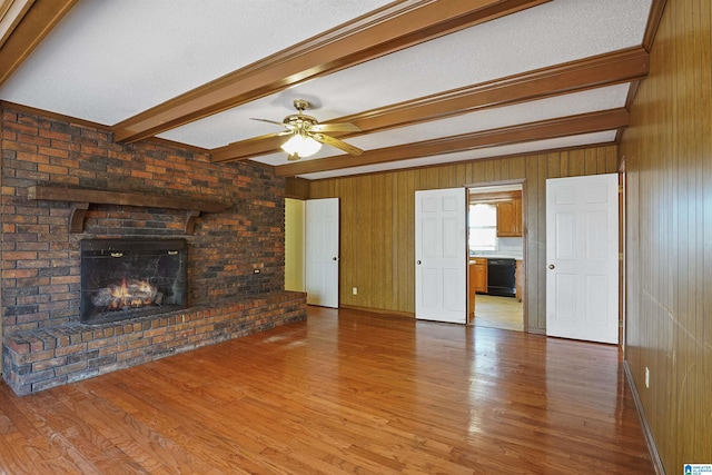 unfurnished living room featuring beamed ceiling, hardwood / wood-style flooring, wooden walls, and a fireplace