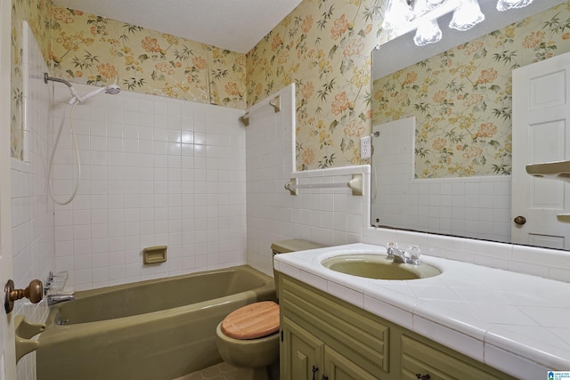 full bathroom with tiled shower / bath, tile walls, vanity, and toilet