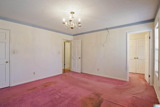 unfurnished room with an inviting chandelier, crown molding, a textured ceiling, and carpet