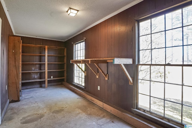 interior space featuring crown molding, wooden walls, and a textured ceiling