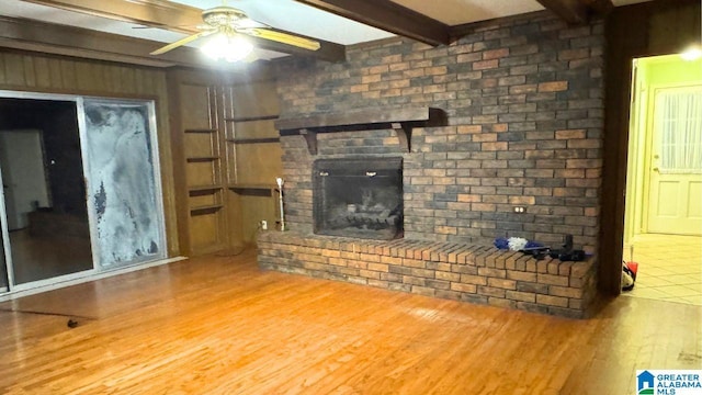 unfurnished living room with beamed ceiling, ceiling fan, hardwood / wood-style flooring, and a fireplace