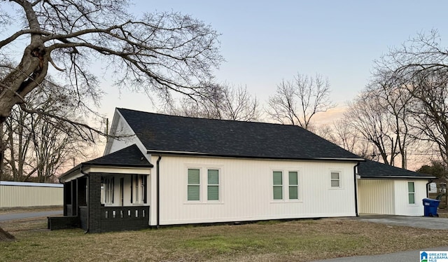 property exterior at dusk with a porch and a yard