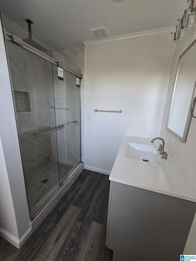 bathroom with hardwood / wood-style flooring, ornamental molding, walk in shower, and vanity