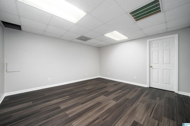 empty room with a drop ceiling and dark wood-type flooring