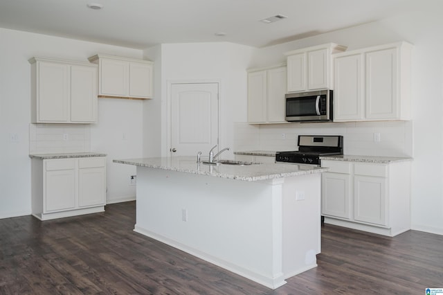 kitchen featuring a kitchen island with sink, white cabinetry, decorative backsplash, and appliances with stainless steel finishes