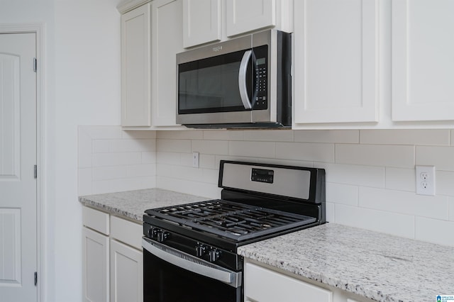 kitchen featuring tasteful backsplash, white cabinetry, light stone counters, and range with gas cooktop