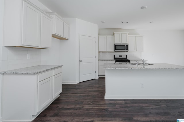 kitchen with light stone countertops, a kitchen island with sink, range, and white cabinets