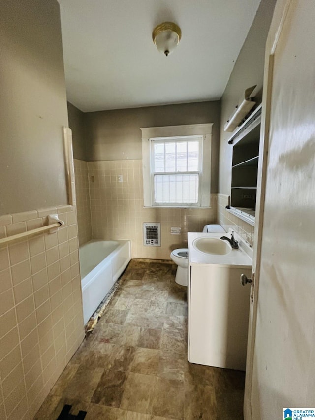 bathroom with tile walls, vanity, heating unit, a tub, and toilet