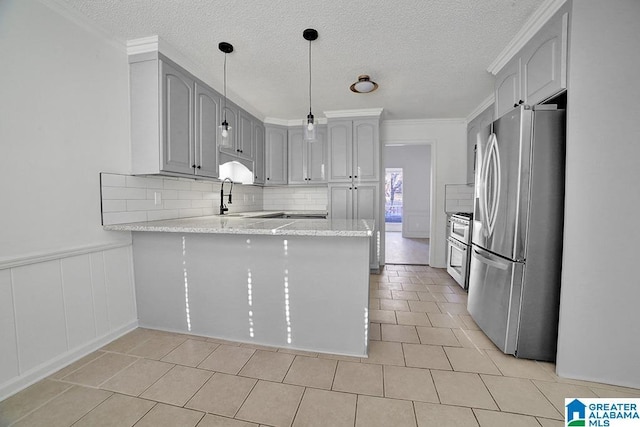 kitchen with light tile patterned flooring, ornamental molding, kitchen peninsula, pendant lighting, and stainless steel appliances