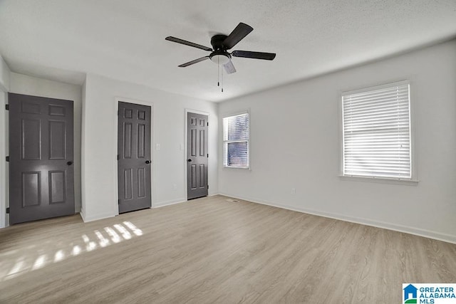 unfurnished bedroom featuring two closets, light hardwood / wood-style floors, and ceiling fan