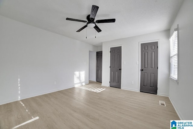 unfurnished bedroom with multiple closets, multiple windows, ceiling fan, and light hardwood / wood-style floors