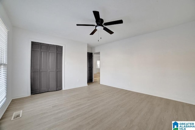 unfurnished bedroom featuring ceiling fan, light hardwood / wood-style floors, and a closet