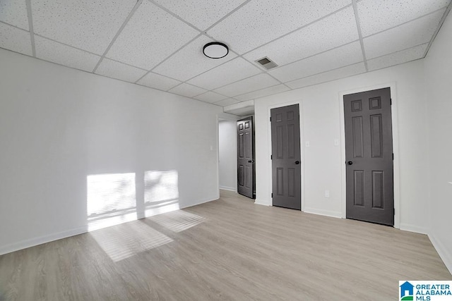 spare room featuring a paneled ceiling and light wood-type flooring