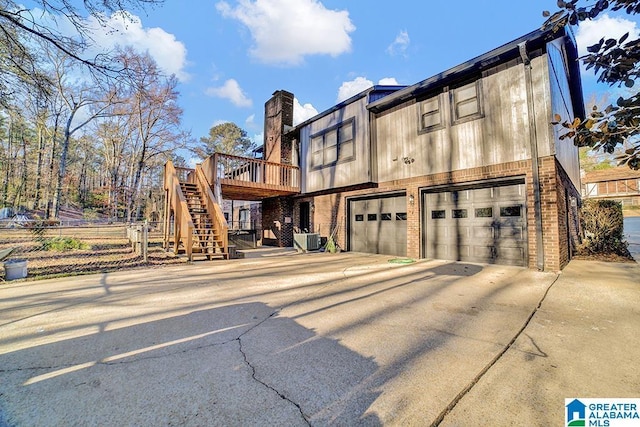 view of property exterior with a garage, a wooden deck, and central AC